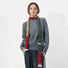 Model wearing long, skinny wool-blend scarf with red, olive, and mustard color blocks and white fuzzy ends.