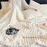 Model resting under cream wave textured fleece blanket, cozy home relaxation view.