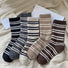 Front view of Five pairs of cozy wool striped crew socks in black, gray, cream, beige, and brown in beige socks.