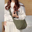 Model wearing the olive green quilted crescent crossbody bag, showing its lightweight and puffy design.