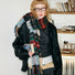 Model wearing a plaid wool scarf in green and red, easy for weekend styling and gifting.
