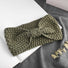 Front view of Olive green  crochet bow headband,on a white book and gray fabric.