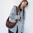 Model wearing the dark brown supple leather shoulder bag with unique pleated construction showcasing sophisticated sculptural aesthetic.
