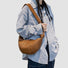 Close-up of caramel croissant bag made of premium faux leather highlighting soft tactile texture and artisanal folds.