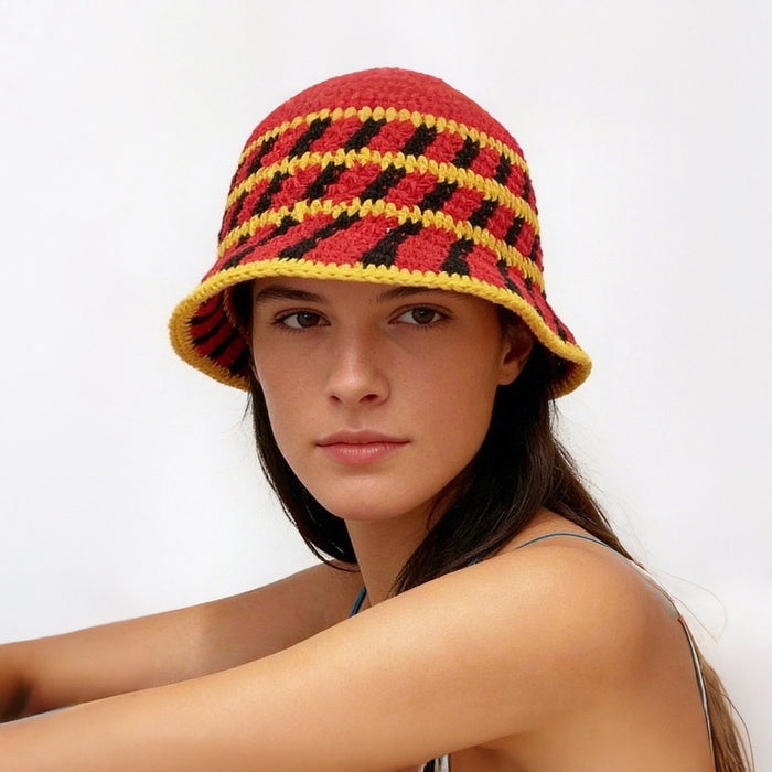Model wearing the red knitted bucket hat, with yellow and black cross striped.