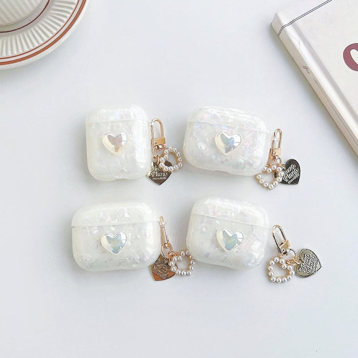Four iridescent white silicone AirPods cases with a heart design and pearl chain charms.