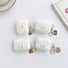 Four iridescent white silicone AirPods cases with a heart design and pearl chain charms.