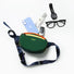 A flat lay of a forest green belt bag with a phone, watch, and glasses, showing its spacious daily organization.