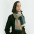Model wearing soft striped scarf in beige, dark green, and white, made of polyester and acrylic.