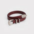 Burgundy leather belt with double keeper loops rolled up showing silver buckle detail.