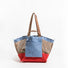 Front view of the blue and red double-sided tote bag featuring a front slip pocket.