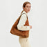 Model carrying the warm tan ease suede hobo bag as a relaxed carryall.