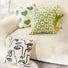Four pieces of Elegant Vibe cotton pillow covers: green hearts, white flowers on green, and abstract face on white.