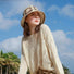 Woman wearing beige straw floral bucket hat with wide brim, perfect for beach sun protection and style.