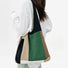 Back view of the Forest green earth-tone woven tote worn by a model, showing the knit strap fit.