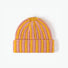 Yellow and coral striped fuzzy beanie displayed flat on a white background.