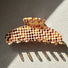 Flat lay of Gentle Curve Claw hair claw clip in brown plaid pattern, easy for workdays and special occasions.
