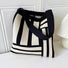 Close-up of Black and white geometric line knitted  bag with elastic shoulder strap and open top .