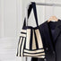Front view of black Geometric Line Knitted Bag hanging on a hanger , great for everyday carry and travel.