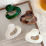 Front view of Four glossy acrylic cloud hair claws in dark green, brown,pure white, and white luster.
