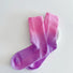 Angled view of  crew-length socks with vibrant pink-to-purple gradient design.