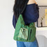 Model wearing an olive green nylon utility bag, perfect for hiking, travel, or a cozy outdoor aesthetic.