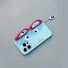 Light blue silicone iPhone case with pink glasses design and dangling eye charm. Eclectic joyful motifs.