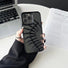 Model holding Hollow Fishbone Phone Case in matte black. Artistic silicone & faux leather hollow design.