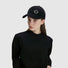 Model wearing Joyful Grin Cap in black, displays iconic smile graphic on a versatile, minimalist streetwear staple.