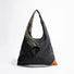 Front view of the Jungle Triangle Tote bag showing the black nylon exterior and olive green handle detail.