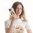 Held by a woman, white silicone case with a yellow smiley face and red hands. Playful Gen-Z fashion.