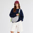 Model wearing a grey knotted crescent bag as crossbody.
