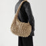 Side view of a model wearing the beige puffy crossbody bag.