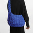 Back view of a model wearing the bright blue puffy crossbody bag.