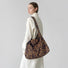 Model carrying the oversized leopard print tote bag as a shoulder bag.