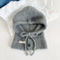 Flat lay of a light grey drawstring buttoned balaclava hat on a white textured background.