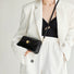 Black PU leather arc baguette shoulder bag with gold clasp, held by a person in a white blazer.