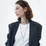 Flat lay of silver teardrop pendant necklace on white fabric, polished jewelry view