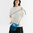 Smiling woman holding a blue nylon Mesh Vogue Crossbody Bag with floral accents and mesh pockets.