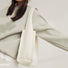 Woman wearing a light grey sweatshirt and a white milk carton textured woven tote bag.