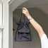 Black mini nylon bucket bag carried as a small handheld utility pouch.