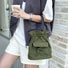 Olive green mini nylon bucket bag worn as a handbag.