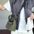 Olive green mini nylon bucket bag worn as a sporty crossbody bag, showing the compact and lightweight fit.