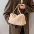 Model carrying a beige mini fluffy shearling baguette bag handheld, great for daily carry and travel.