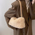 Model carrying a beige mini fluffy shearling baguette bag on the shoulder, easy for commuting and weekends.