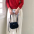 Model holding the classic black saddle bag with a  minimalist look.