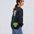 A model wearing a green triangle mini bag as a crossbody, highlighting the geometric style impact.