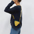 A model wearing a yellow triangle mini bag as a crossbody, highlighting the geometric style impact.