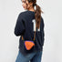 A model wearing an orange triangle mini bag as a crossbody, highlighting the geometric style impact.