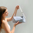Model holding the striped baguette bag, highlighting its structured canvas shape.